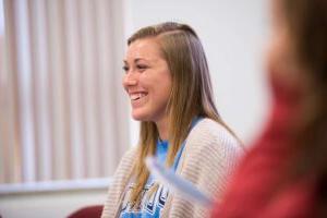 A close up of a female student smiling in a classroom.